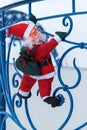 Toy Santa Claus climbs the railing of the balcony of the cottage