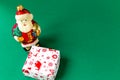 Toy Santa Claus and gift box on a green background. Top view