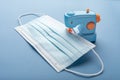 Toy sewing machine sews medical surgical protective mask for coronavirus. Concept on topic of covid close-up on blue background