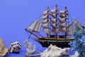 Toy ship on a blue background. Near many seashells