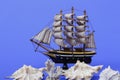 Toy ship on a blue background. Near many seashells