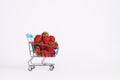 Toy shopping cart or trolley full of ripe large red strawberries isolated on white background. Berry harvest sale Royalty Free Stock Photo