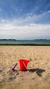 Toy shovel and red bucket on  beach in summer day Royalty Free Stock Photo