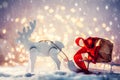 Toy sleigh with a Christmas gift pulled by a wooden reindeer in snow Royalty Free Stock Photo