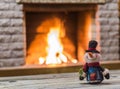 Toy snowman aginst the background of the fireplace. Royalty Free Stock Photo