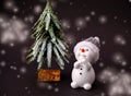 Toy snowman with a Christmas tree on a black background. A white snowman makes a wish on new year`s eve. Photo for a Royalty Free Stock Photo