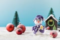 Toy snowman and red balls on fake snow near small house in decorative forest Royalty Free Stock Photo