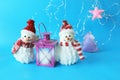 Toy snowman in a Santa hat, lantern with a lit candle on a blue bright background Royalty Free Stock Photo