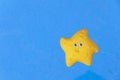 Yellow toy starfish on blue surface background Royalty Free Stock Photo