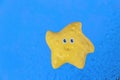 Yellow toy starfish on blue surface background Royalty Free Stock Photo