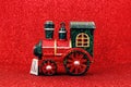 Toy steam train locomotive on red glitter background. Christmas tree toy