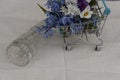 A toy supermarket cart with a bouquet of bright spring flowers