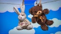 Toy Teddy bear and rabbit are suspended from the rope clothespins on a background of cartoon white clouds Royalty Free Stock Photo