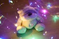 A toy teddy bear surrounded by colored lights. Abstract fairytale magic background