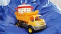 Toy tipper truck with pan in workbody stands on blue bag chair