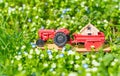 Toy Tractor Carrying a Miniature House on a Flowerbed