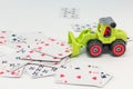 The toy tractor clears the white table from the playing cards. gorzontal photo, soft focus., white background