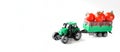 Toy tractor with a trailer loaded with fresh red cherry tomatoes. White background. The concept of agricultural work, harvesting Royalty Free Stock Photo