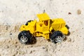 Toy tractor in the wet sand. Summer holidays at sea. Special miniature.