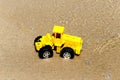 Toy tractor in the wet sand. Summer holidays at sea. Special miniature.