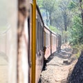 Toy Train moving on mountain slopes, beautiful view, one side mountain, one side valley moving on railway to the hill, among green Royalty Free Stock Photo