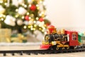 Toy train and railway on floor against Christmas lights Royalty Free Stock Photo