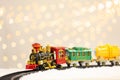 Toy train and railway on snow against Christmas lights Royalty Free Stock Photo