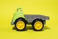 Toy truck car on a yellow background - construction equipment for children. Bright children`s plastic toys, dump truck