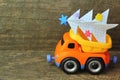 Toy truck carrying hand made paper christmas tree against rough wooden background. Side view. Christmas tree recycle or disposal, Royalty Free Stock Photo