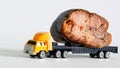 Toy truck with a trailer is transporting a large piece of smoked salmon. White background. The concept of the delivery of fish and Royalty Free Stock Photo