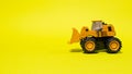 Toy typewriter tractor bulldozer on a yellow background. Toy for children Royalty Free Stock Photo