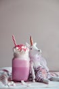 Toy unicorn with pink milk shake with cream, marshmallow and colorful decoration. Milk shake, cocktail. Unicorn coffee. Royalty Free Stock Photo