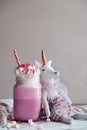 Toy unicorn with pink milk shake with cream, marshmallow and colorful decoration. Milk shake, cocktail. Unicorn coffee. Royalty Free Stock Photo