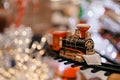 toy vintage steam locomotive on the floor under a decorated Christmas tree on a background of bokeh lights garland Royalty Free Stock Photo