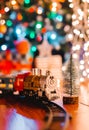 Toy vintage steam locomotive on the floor under a decorated Christmas tree on a background of bokeh lights garland. Royalty Free Stock Photo