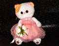 Toy white cat on a black background in a pink dress Royalty Free Stock Photo