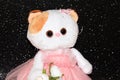 Toy white cat on a black background in a pink dress Royalty Free Stock Photo