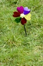 Toy windmill flower on green grass background,concept of green energy.