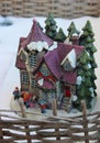 Toy winter yard fenced wattle hedge with a house and family figurines on the porch Royalty Free Stock Photo