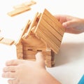 Toy wooden house. Child builds small house. Dream about home. Small model of house from wooden blocks