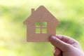 Toy wooden house in hand on a light green background, Concept - buying a house on credit or mortgage, safe and affordable housing