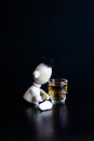 Toy wooden man peeks into a glass of wine on a black background. The concept of drunkenness, alcoholism