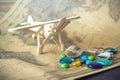 Toy wooden plane on a world map with colored stones and shells from the sea in a retro style. Royalty Free Stock Photo