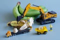 Toy workers, hydraulic hammer and trucks next to yellow and green bananas. Blue background. The concept of collecting and Royalty Free Stock Photo