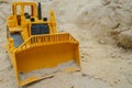 A toy yellow bulldozer digs the sand.