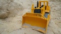 A toy yellow bulldozer digs the sand.