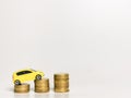 Toy yellow car on roll stair step of coins. Increament in vehicle expences and price concept.