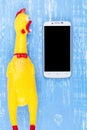 Toy yellow shrilling chicken on blue wooden background with smartphone and copy space .Template mock up for adding your design Royalty Free Stock Photo