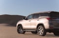 Toyota Fortuner standing in the middle of the Namib desert on a sunny day.