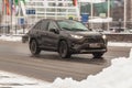 Toyota RAV4 XA50 SUV vehicle on the city road. Fast moving black crossover car on streets with dirty melt snow